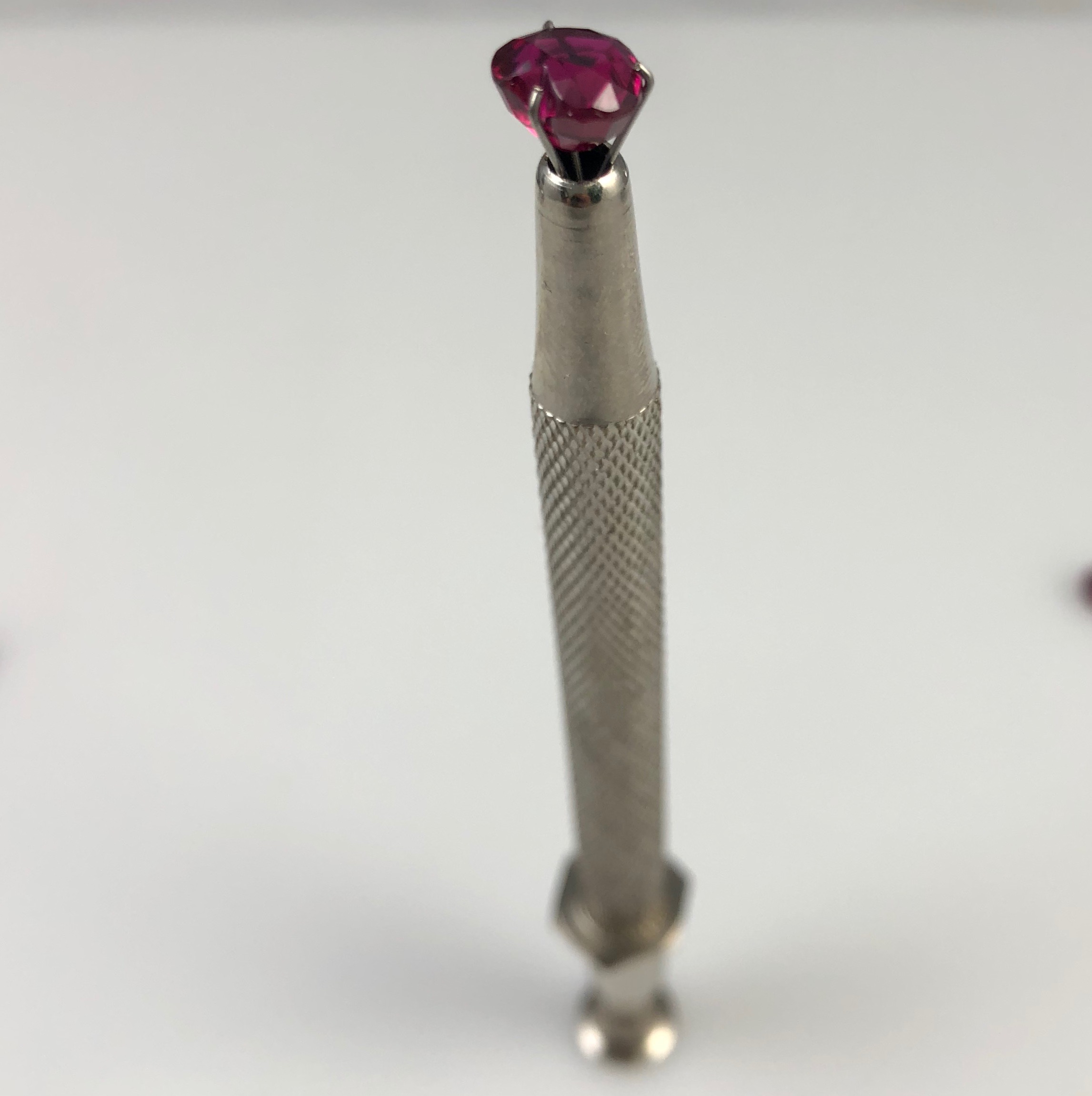 A cushion-cut ruby gripped in the jaws of a stone setter's holding tool