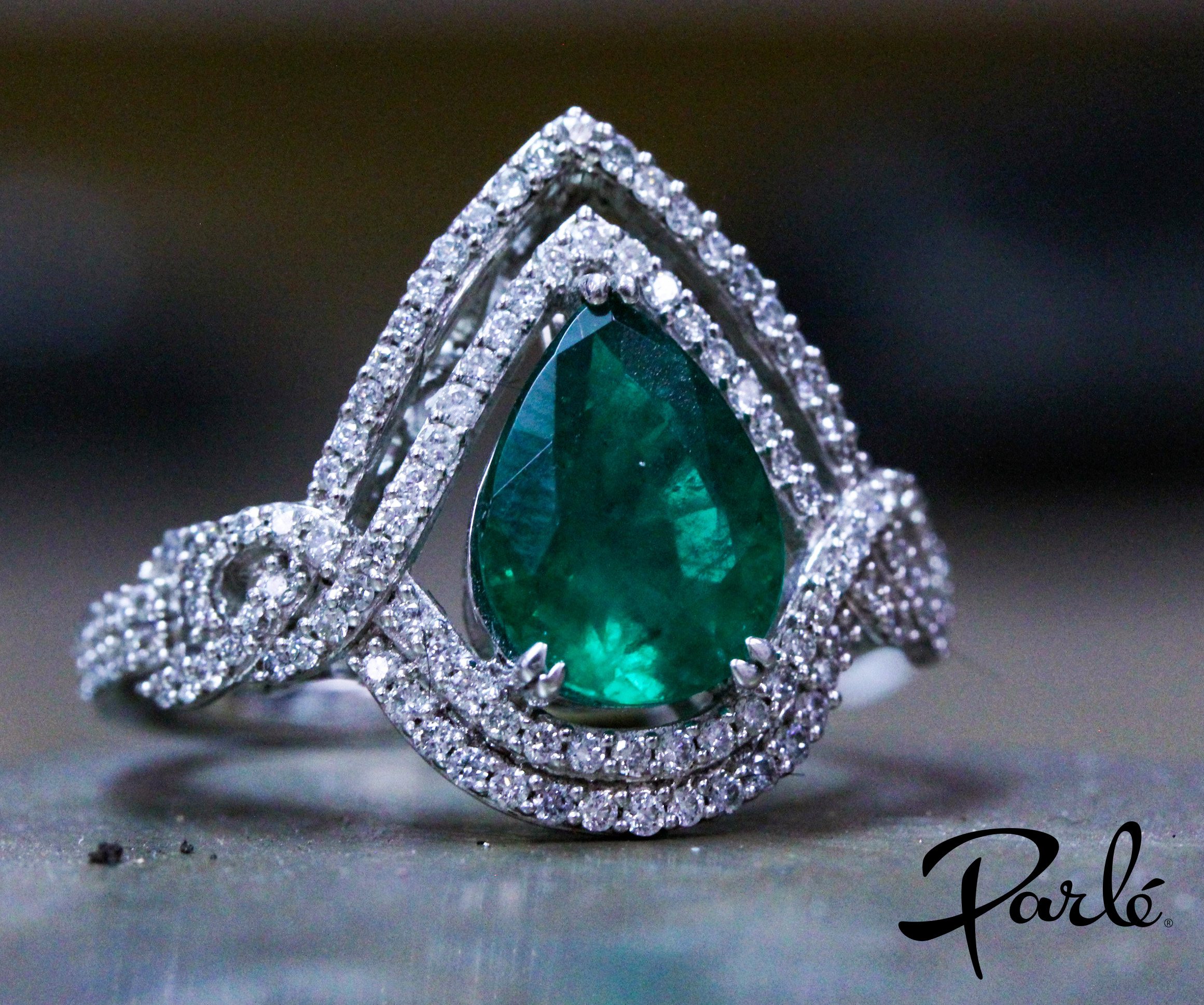 Pear-shaped emerald ring surrounded by a double halo of diamonds