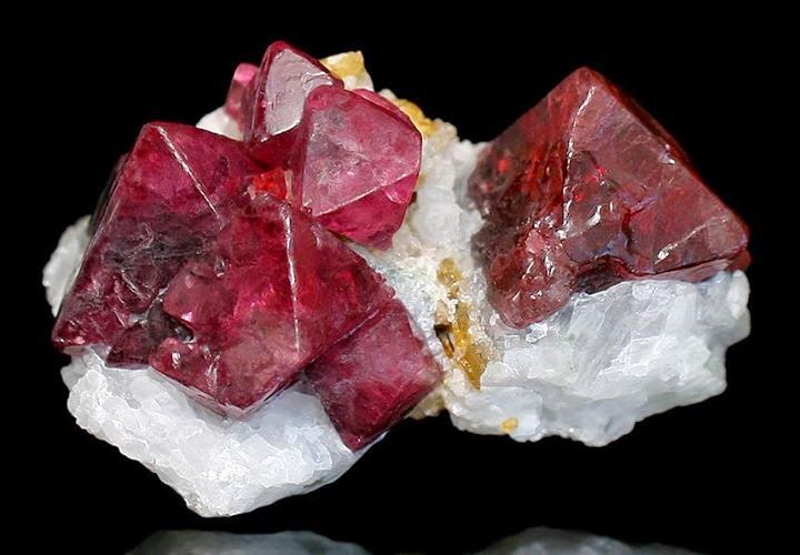 A cluster of red spinel crystals in their natural octahedral shape on white matrix
